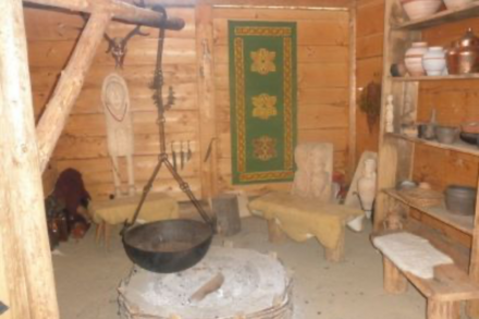 Inneneinrichtung eines traditionellen Keltenhauses. Kessel über Feuerstelle, Holzsitzbank und Holzregal mit Utensilien